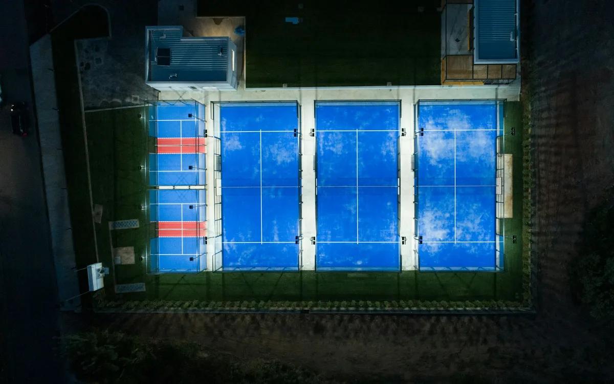 Beleuchtete Padel-Courts aus der Luft bei Nacht