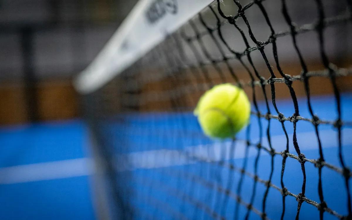 Padelball im Netz auf einem blauen Court
